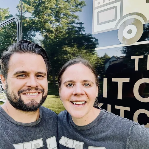 The owners of The Hitched Kitchen standing in front of their mobile kitchen trailer